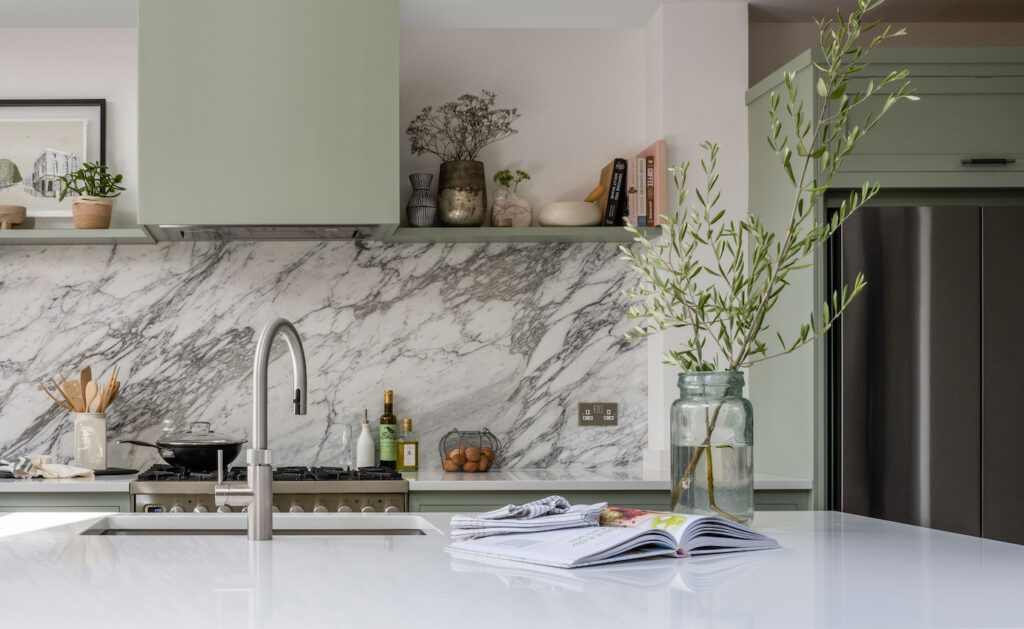 White marble kitchen island worktop with silver tap overlooking a white marble splashback